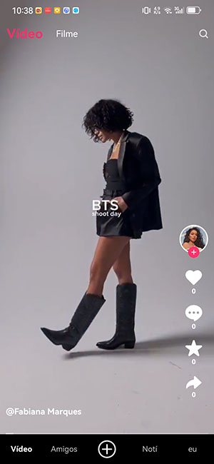 Screenshot of a girl in black boots and shorts dancing in front of a gray wall, with music icons on the right